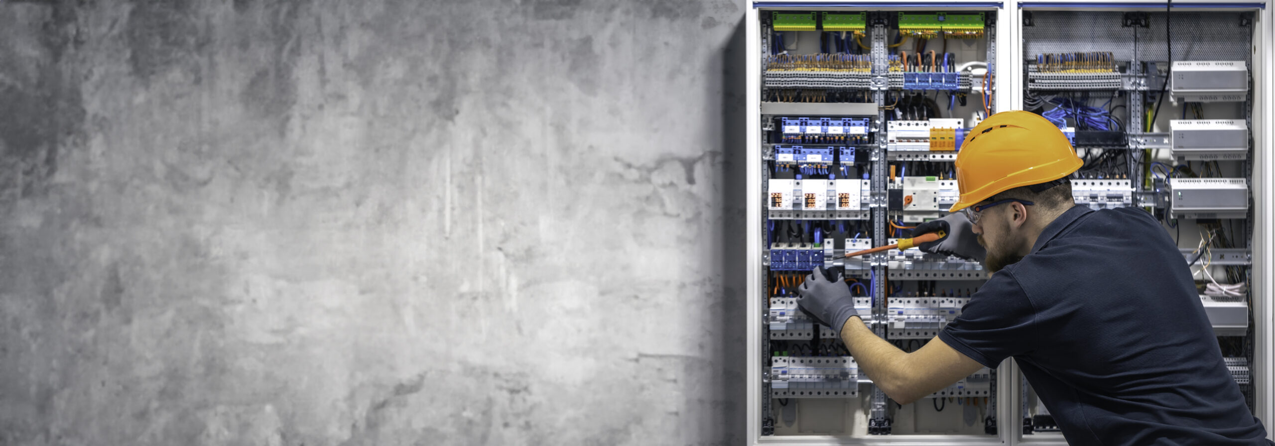 Electrician working in switchboard with electrical connection cable, copy space.